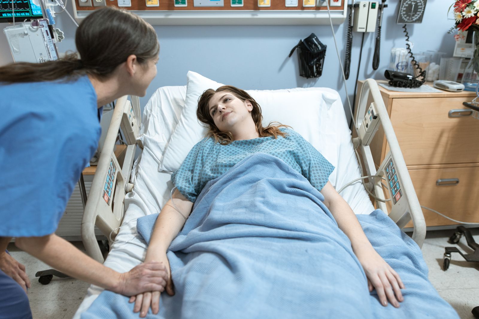 A caregiver sitting beside a patient in a bright hospital room.